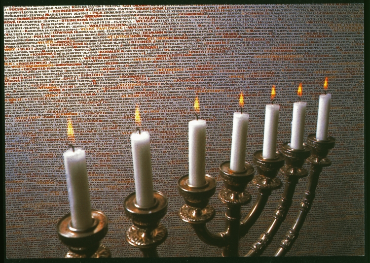 Memorial candles burning before the handwritten names of Czech Holocaust victims on the Pinkas Synagogue wall