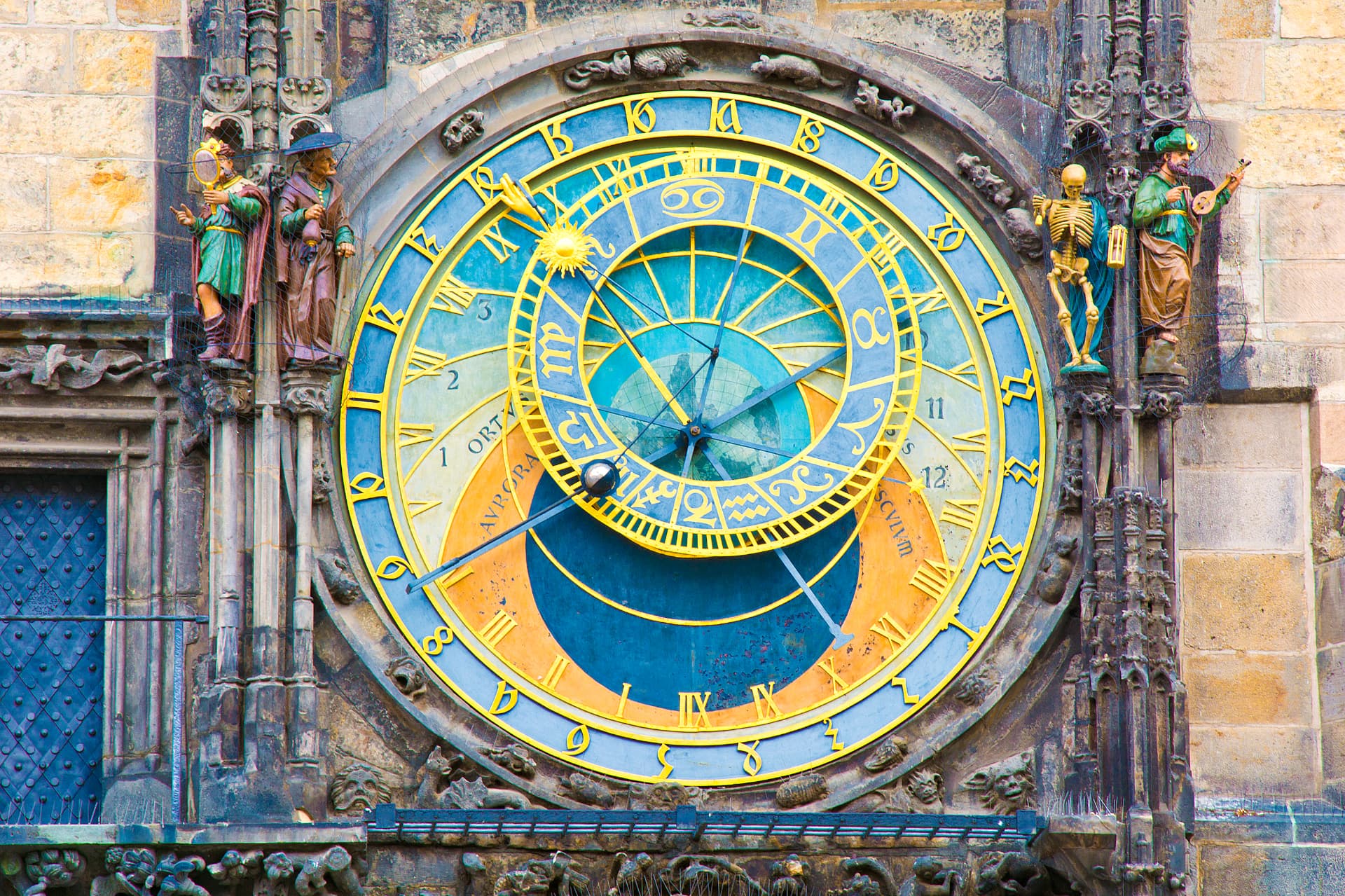 Close-up of Prague's medieval astronomical clock with its blue and gold dial and carved figures